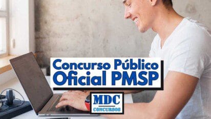 Homem jovem sorridente usando camiseta branca digita em um notebook sobre uma mesa de madeira clara ao lado de uma janela com luz natural entrando. Ao centro da imagem, há um banner com os dizeres "Concurso Público Oficial PMSP" em letras grandes azuis e, logo abaixo, o logotipo da MDC Concursos em azul escuro com fundo claro