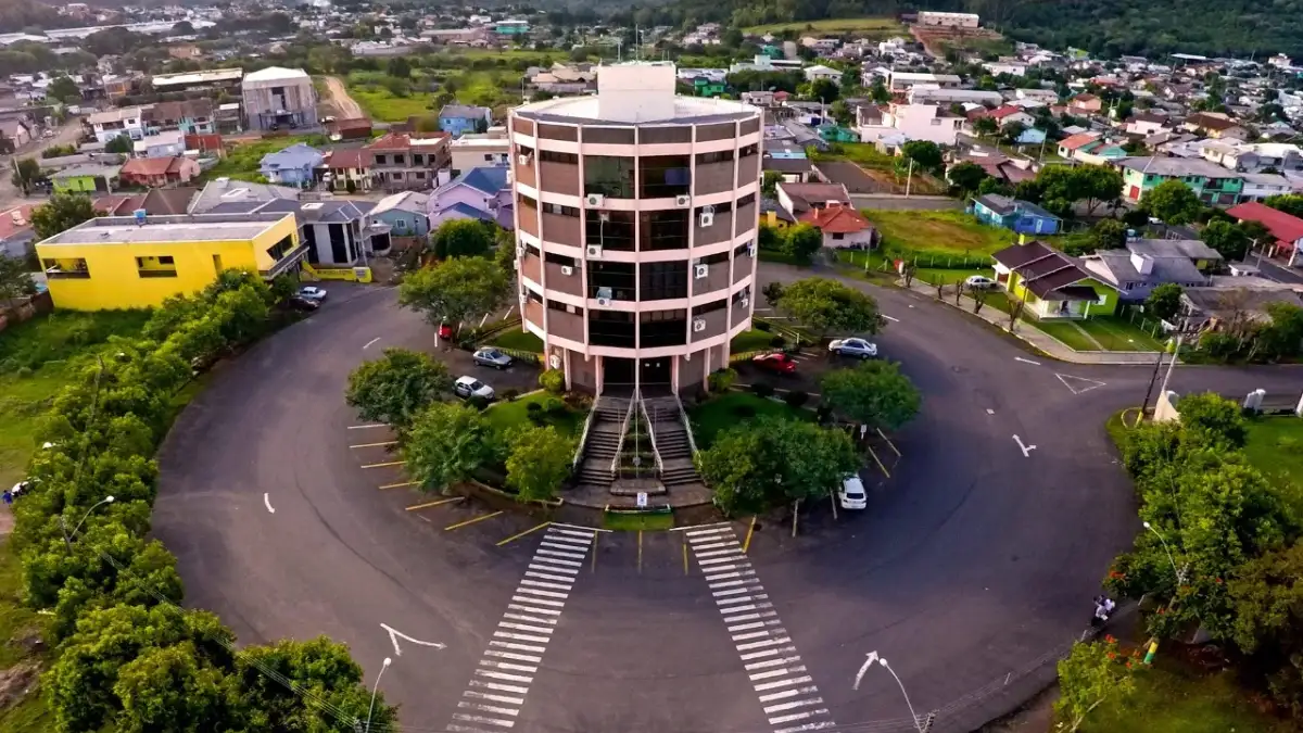Concurso Parobé RS 2026 tem banca definida para 153 vagas de professores 1 Foto aérea do prédio da Prefeitura de Parobé RS, edifício cilíndrico rodeado por rotatória e área verde, concurso Parobé RS