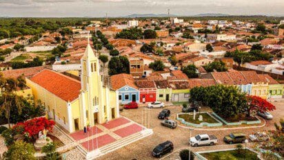 Vista aérea de uma praça central com igreja amarela, casas coloridas e ruas arborizadas em uma cidade pequena. Foto: Divulgação/Prefeitura de Congo-PB