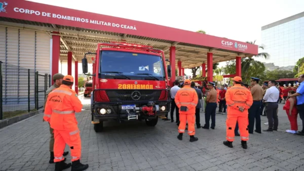 Bombeiros militares em uniformes laranja posicionados em frente a um caminhão de resgate vermelho no pátio do CISP Ceará. Foto: Divulgação/CBMCE