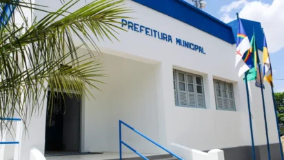 Fachada da Prefeitura Municipal de Riacho das Almas-PE, em prédio branco e azul, com bandeiras hasteadas e entrada principal com corrimão azul. Foto: Divulgação/Prefeitura de Riacho das Almas-PE