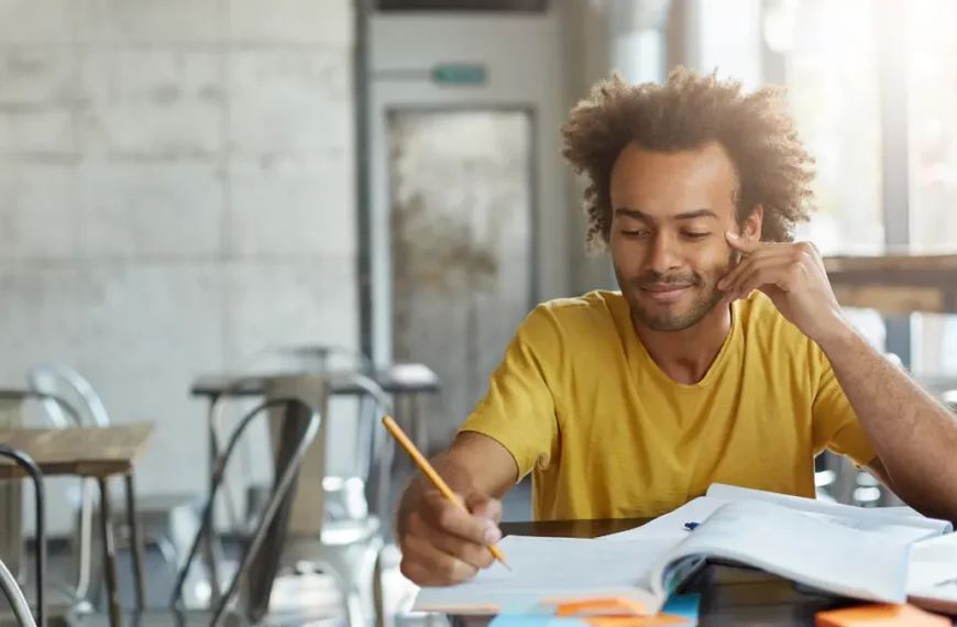 Homem estudando em mesa com livros e laptop em ambiente claro e moderno. Foto: wayhomestudio/Freepik