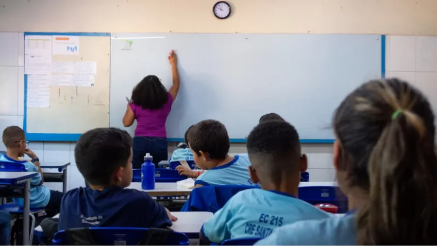 Concurso SEDF: sala de aula com professora escrevendo no quadro e alunos assistindo à aula