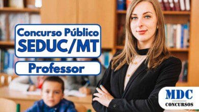 Professora jovem de pé com os braços cruzados em sala de aula, sorrindo, com três alunos ao fundo estudando em carteiras - Concurso SEDUC MT 2025 abre 1500 vagas para Professores da Educação Básica