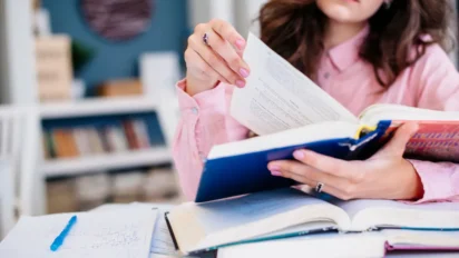 Pessoa estudando em mesa com livros abertos e anotações. Foto: Freepik