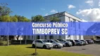 Prédio da Prefeitura Municipal de Timbó ao fundo com faixa azul e texto Concurso TimboPrev SC
