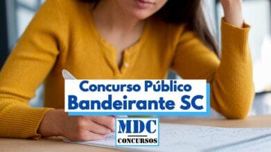 Mulher vestindo blusa amarela aparece sentada à mesa, segurando uma caneta enquanto observa atentamente uma folha de papel à sua frente, indicando momento de estudo ou preparação para prova. Em destaque, uma faixa azul centralizada sobre a imagem exibe o texto “Concurso Público Bandeirante SC” e abaixo o logotipo “MDC Concursos”, sugerindo divulgação de concurso público em Santa Catarina.