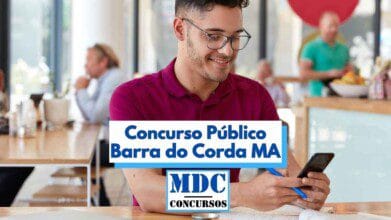 Homem jovem de óculos e camisa polo vinho está sentado em um ambiente moderno e iluminado, utilizando o celular e sorrindo, com uma caneta azul na mão e caderno sobre a mesa. Ao fundo, outras pessoas conversam em mesas. Sobre a imagem há um banner com os dizeres “Concurso Público Barra do Corda MA” e o logotipo “MDC Concursos” centralizado na parte inferior.