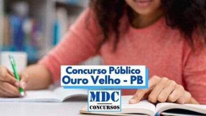 Mulher de blusa coral estuda em uma biblioteca, com livros abertos à sua frente, enquanto escreve com caneta verde. Sobre a imagem, há um banner com os dizeres "Concurso Público Ouro Velho - PB" em letras azuis, e abaixo o logotipo "MDC Concursos". A imagem transmite foco e preparação para concursos públicos.