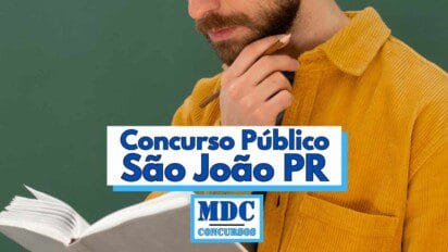 Homem com barba e camisa de veludo cotelê amarela aparece segurando um lápis próximo ao rosto e um caderno aberto, em frente a um fundo verde, sugerindo ambiente escolar ou de estudo; sobre a imagem há um destaque em letras azuis com a frase “Concurso Público São João PR” e o logotipo da MDC Concursos logo abaixo do texto principal