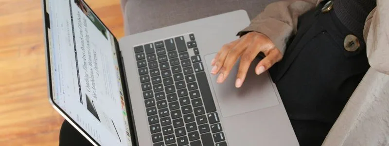 Pessoa utilizando um notebook com a mão sobre o teclado.
