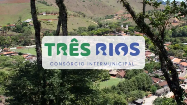 Consórcio Três Rios/SP abre seleção com salários de até R$ 3.268,29 2 Vista aérea de uma pequena cidade rodeada por montanhas verdes, com o logotipo do Consórcio Intermunicipal Três Rios em destaque no centro da imagem sobre um fundo branco arredondado.