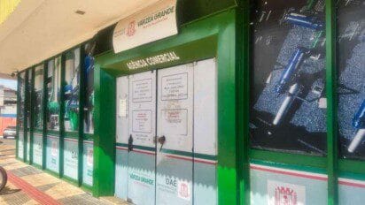 Fachada da agência comercial do DAE de Várzea Grande com portas fechadas, letreiro visível e imagens de encanamentos nas paredes externas.