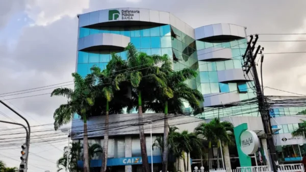 Fachada de prédio moderno da Defensoria Pública do Estado da Bahia com vidros espelhados, palmeiras em frente e logotipo da instituição no topo. Foto: Divulgação/DPE-BA