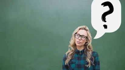 Diferença entre concurso e processo seletivo: Mulher com expressão pensativa diante de um fundo verde, usando óculos e camisa xadrez, com balão de pensamento contendo um ponto de interrogação. Foto: creativeart/Freepik