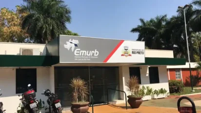 Fachada da sede da EMURB em São José do Rio Preto com logotipos da empresa e da Prefeitura, rodeada por palmeiras e motocicletas estacionadas em frente. Foto: Divulgação/EMURB