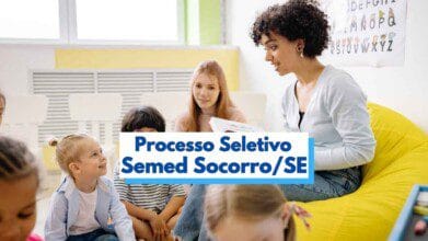 Imagem de uma sala de aula infantil com crianças sentadas no chão, interagindo com duas professoras. Uma das educadoras, sentada em uma poltrona amarela, segura um livro e conversa com os alunos, enquanto a outra observa. Ao fundo, há uma parede clara com alfabeto ilustrado. Sobre a imagem, há um banner com os dizeres “Processo Seletivo Semed Socorro SE” em destaque.