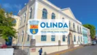 Fachada de um casarão histórico de cor amarela com janelas azuis, onde se vê o logotipo da Prefeitura de Olinda centralizado sobre a imagem. Foto: Divulgação/Prefeitura de Olinda-PE