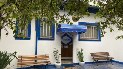 Fachada da sede da FUNCABES com paredes brancas, detalhes azuis, bancos de madeira e entrada com toldo azul. Foto: Divulgação/FUNCABES