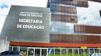 Fachada da Secretaria de Educação da Prefeitura de Feira de Santana com letreiro em destaque e fachada moderna com painéis de vidro e ripas verticais