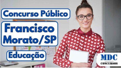 Mulher sorridente com óculos e coque no cabelo, vestindo camisa vermelha com estampa de corações brancos, segurando um notebook em um escritório com quadro de anotações ao fundo - Francisco Morato (SP) oferece remuneração de até R$ 4mil em Concurso na Educação