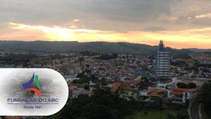 Vista panorâmica de uma cidade ao pôr do sol com prédios e morros ao fundo, sobreposta pelo logotipo da Fundação do ABC. Foto: Montagem MDC Concursos/Victorcec - Wikipédia