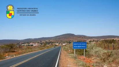 Rodovia de acesso a Gentio do Ouro, na Bahia, com placa de boas-vindas à cidade, área urbana ao fundo e paisagem típica do sertão sob céu azul. Foto: Divulgação/Prefeitura de Gentio do Ouro-BA