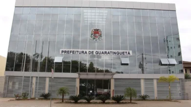 Guaratinguetá/SP abre processo seletivo com 28 vagas de até R$ 6.225,76 2 Fachada do prédio da Prefeitura de Guaratinguetá com estrutura moderna em vidro espelhado, brasão oficial ao centro e identificação do órgão acima da entrada principal. Foto: Divulgação/Prefeitura de Guaratinguetá-SP