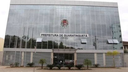 Fachada do prédio da Prefeitura de Guaratinguetá com estrutura moderna em vidro espelhado, brasão oficial ao centro e identificação do órgão acima da entrada principal. Foto: Divulgação/Prefeitura de Guaratinguetá-SP