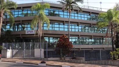 Fachada do prédio da IMA em Campinas, com estrutura moderna de três andares, janelas espelhadas, palmeiras na frente, grade de proteção e logotipo da empresa na entrada. Foto: Divulgação/Prefeitura de Campinas-SP