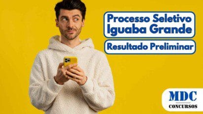 Homem jovem de pele clara e cabelos escuros segurando um smartphone amarelo e olhando para o lado com expressão curiosa, vestindo um moletom branco de pelúcia, em frente a um fundo amarelo sólido - Iguaba Grande (RJ) Divulga Resultado Preliminar de Processo Seletivo 2025