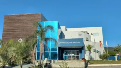 Fachada moderna do prédio da Prefeitura de Imbituba-SC com vidro azul, palmeiras e céu limpo ao fundo. Foto: Divulgação/Prefeitura de Imbituba-SC