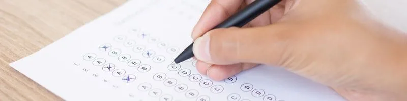 Patos - PB abre concursos com 560 vagas de até R$ 5.513,94 2 Pessoa segura uma caneta preta enquanto preenche uma folha de respostas com bolhas típicas de provas objetivas em concursos ou exames. A mão está em foco e a folha mostra alternativas de A a E, com algumas já marcadas. A imagem sugere um ambiente de avaliação, simbolizando a etapa de prova escrita ou múltipla escolha comum em processos seletivos e concursos públicos