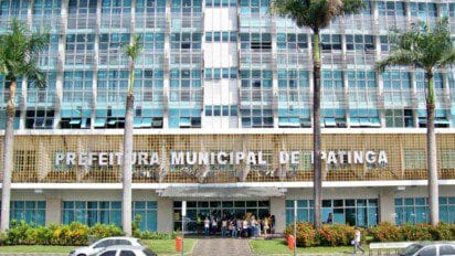 Fachada do prédio da Prefeitura Municipal de Ipatinga com letreiro em destaque e pessoas reunidas na entrada.