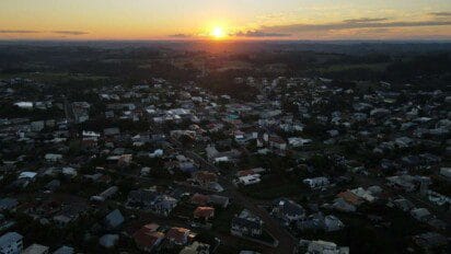 Vista aérea de Iporã do Oeste, SC, ao entardecer, com o sol se pondo no horizonte e casas distribuídas em área urbana rodeada por vegetação. Foto: Divulgação/Prefeitura de Iporã do Oeste-SC