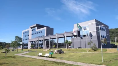 Prédio da Prefeitura de Itaúna, em Minas Gerais, com fachada moderna de vidro, bandeiras hasteadas e área verde ao redor. Foto: Divulgação/Prefeitura de Itaúna-MG