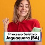 Mulher jovem com expressão de felicidade veste camisa vermelha e segura um celular verde, olhando para a tela com entusiasmo. Ela faz um gesto de comemoração com a mão esquerda cerrada, indicando uma boa notícia. Ao fundo, há um cenário de cor laranja vibrante. Na parte inferior da imagem, há uma faixa com os dizeres “Processo Seletivo Jaguaquara (BA)”, destacando uma oportunidade de emprego.