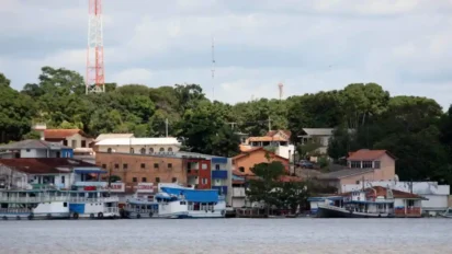 Vista de casas e embarcações ancoradas às margens de um rio em Juruti, com área arborizada e torres de comunicação ao fundo. Foto: Divulgação/Governo do Pará