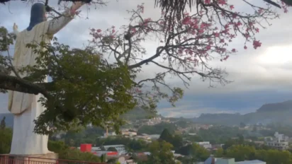 Vista panorâmica de Laurentino SC com estátua de Cristo de braços abertos em primeiro plano, árvores floridas e a cidade ao fundo entre morros. Foto: Divulgação/Prefeitura de Laurentino-SC