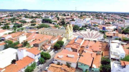 Vista aérea de Limoeiro do Norte, no Ceará, com destaque para a igreja matriz, praça central e construções com telhados vermelhos ao redor.