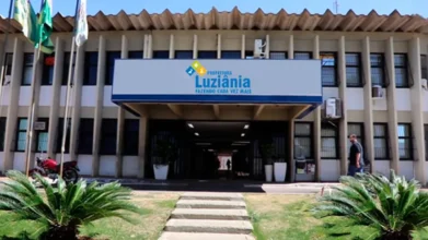 Fachada da Prefeitura de Luziânia com placa institucional, entrada central coberta, bandeiras hasteadas e jardim frontal durante o dia. Foto: Divulgação/MPGO