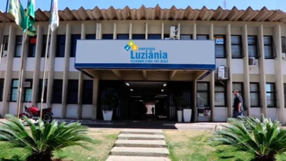 Fachada da Prefeitura de Luziânia com placa institucional, entrada central coberta, bandeiras hasteadas e jardim frontal durante o dia. Foto: Divulgação/MPGO