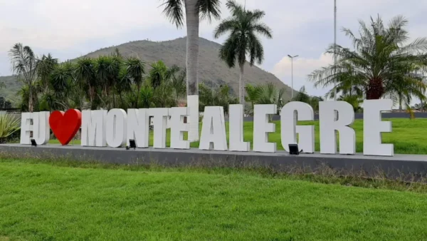 Letreiro turístico “Eu amo Monte Alegre” em área verde, com palmeiras ao redor e morro ao fundo, representando a cidade de Monte Alegre de Goiás. Foto: Divulgação/Prefeitura de Monte Alegre de Goiás