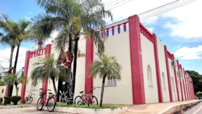 Fachada da Prefeitura de Nossa Senhora do Livramento com prédio histórico em tons de bege e vermelho, palmeiras na calçada, bicicletas estacionadas e céu azul ao fundo. Foto: Divulgação/Prefeitura de Nossa Senhora do Livramento-MT