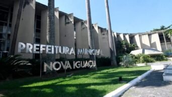 Fachada da Prefeitura Municipal de Nova Iguaçu com letreiro metálico em destaque e palmeiras ao redor. Foto: Divulgação/Prefeitura de Nova Iguaçu-RJ