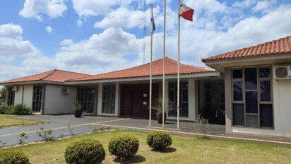 Fachada da Prefeitura de Nova Santa Rosa, PR, com jardim em frente, bandeiras hasteadas e céu com nuvens ao fundo. Foto: Divulgação/Prefeitura de Nova Santa Rosa-PR