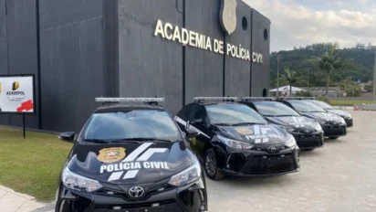 Viaturas da Polícia Civil de Santa Catarina estacionadas em frente ao prédio da Academia de Polícia Civil, com fachada escura e identificação institucional. Foto: Divulgação/PCSC
