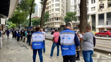 Servidores do Procon/RJ com coletes azuis realizam atendimento ao público em calçada do Centro do Rio de Janeiro, com prédios e pedestres ao fundo. Foto: Divulgação/Procon/RJ