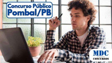Homem jovem de camisa xadrez trabalhando em um notebook enquanto segura uma caneta, sentado à mesa com vaso de planta ao lado, em ambiente iluminado por janelas de vidro fosco - Pombal (PB) abre 213 vagas com salários de até R$ 4,7 mil em Concurso Público