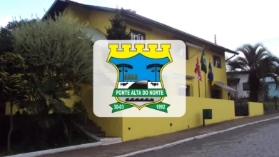 Fachada da prefeitura de Ponte Alta do Norte, prédio amarelo com bandeiras e o brasão do município em destaque no centro da imagem.